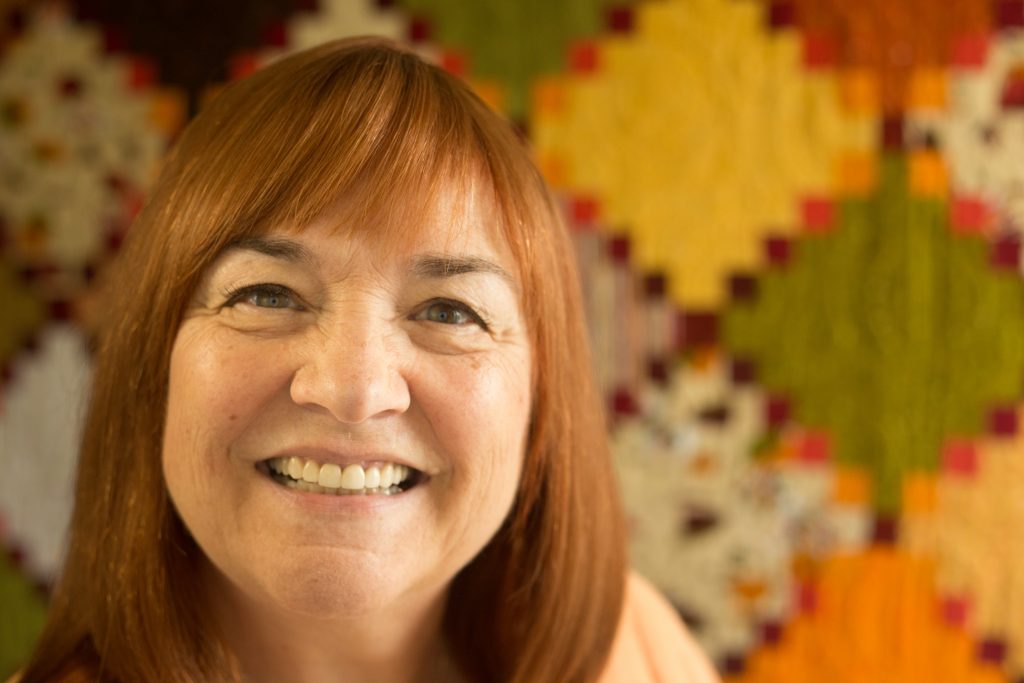 Photo of guest speaker Annie Smith in front of a quilt