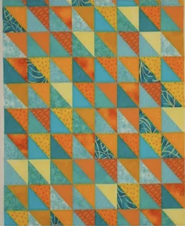 Quilt top with orange and green half-square triangles, made using a tube piecing technique.